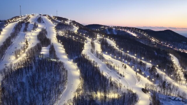 Aerial drone view of illuminated Bromont ski resort slopes at dusk, Quebec, Canada in winter. g.