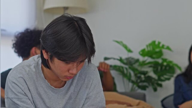 Depressed young man looking down with somber expression during gathering