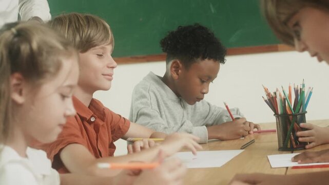 Children engaged in creative learning and drawing activity together inside classroom environment.
