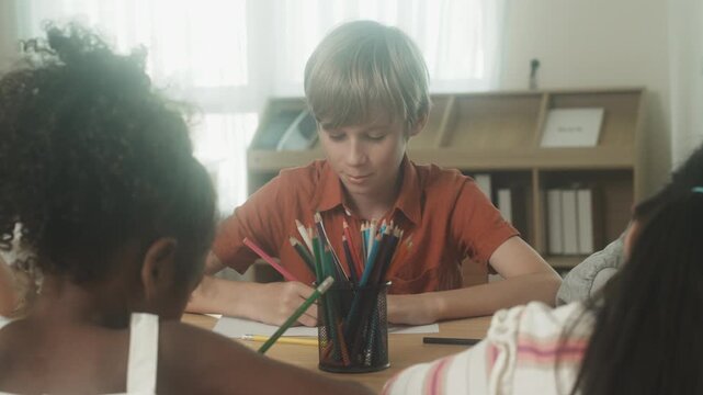 Children engaged in creative learning and drawing activity together inside classroom environment.
