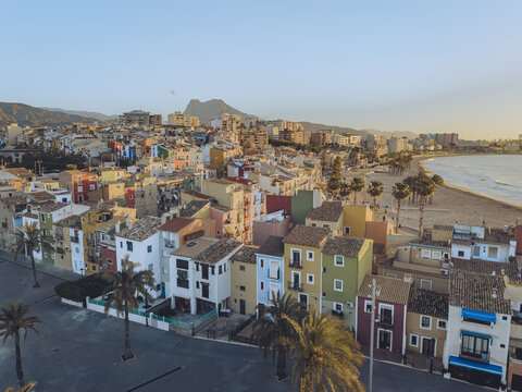 Aerial view of the iconic colorful houses along the Mediterranean coast with a sandy beach and palm trees in La Vila Joiosa, Valencian Community, Spain.