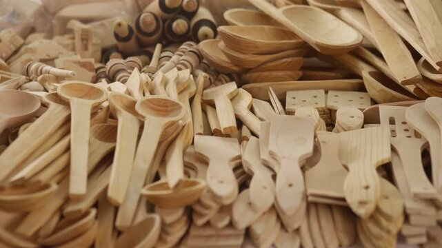 Close view of carved wooden objects and utensils arranged in pile, artisan craftsmanship detail