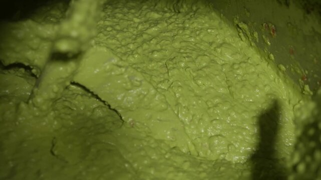 Dense avocado paste with smooth texture filling frame during food processing stage