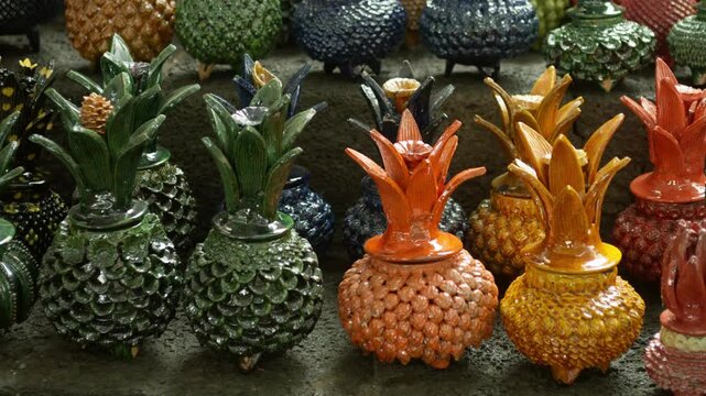 Assorted colorful pineapple shaped crafts arranged in rows at artisan market stall
