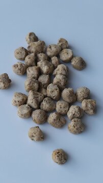 dry soya chunks scattered on a plain white background