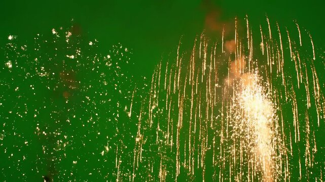 Two bursts of golden fireworks against green sky emphasizing fluid motion and vibrant color palettes
