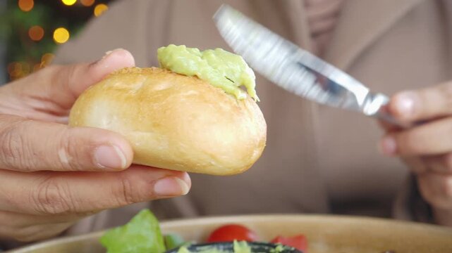 Close-up of Hands Spreading Avocado on a Bread Roll