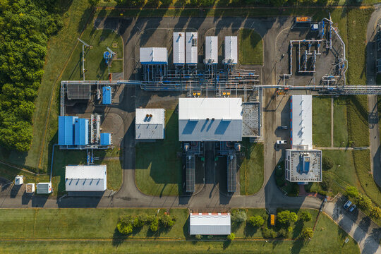 Aerial view of the UGS Damborice industrial facility with white and blue buildings, complex piping systems, and asphalt roads in Damborice, South Moravian Region, Czechia.