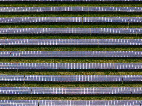 Aerial view of rows of solar panels arranged in a geometric pattern on a green field Sivice, South Moravian Region, Czechia.