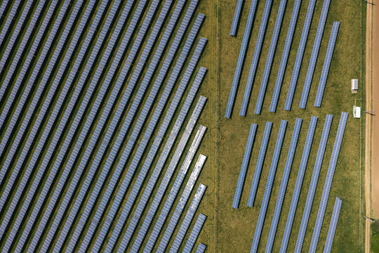 Aerial view of rows of solar panels in a large photovoltaic power plant on green fields Sivice, South Moravian Region, Czechia.