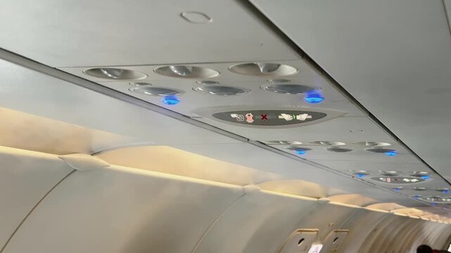 Close up of strong cold condensate in Airplane Cabin. Overhead Panels with Air Conditioning Vents and Safety Signs