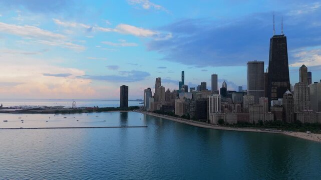 Stunning aerial view of Chicago downtown skyline along Lake Michigan waterfront during golden hour sunset. Boats float near Navy Pier as dramatic clouds fill the sky above iconic skyscrapers.