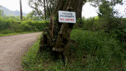 Naklejka premium Private Property No Entry Sign Posted on Tree Along Rural Path