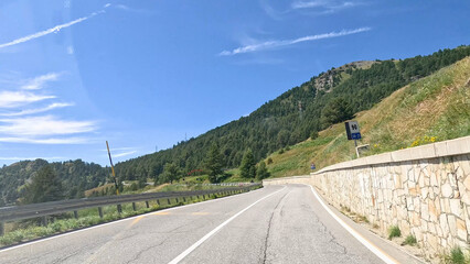 Naklejka premium Winding Mountain Road with Stone Wall in Piedmont Italy Under Blue Sky