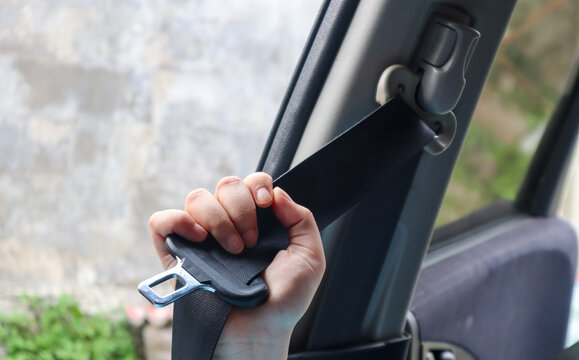 Close up of hand pulling car seat belt before driving inside vehicle, road safety and transportation protection concept in modern car interior.