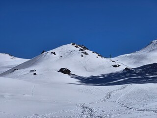 Obraz premium Snowy winter landscape with trekking trails and tiny hikers at Gorson Bugyal, Uttarakhand
