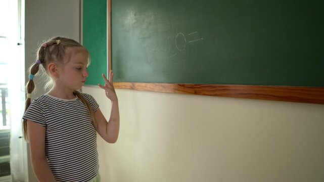 Young students are calculating the result of numbers to write the answer on the blackboard at the front of the classroom. This is a math activity for elementary school classrooms