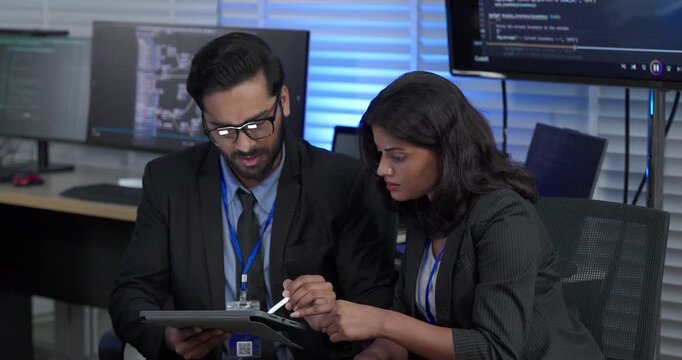 Two professionals analyze and discuss programming code displayed on screen in modern tech workspace. Capturing a collaborative environment focused on software development, debugging, and teamwork
