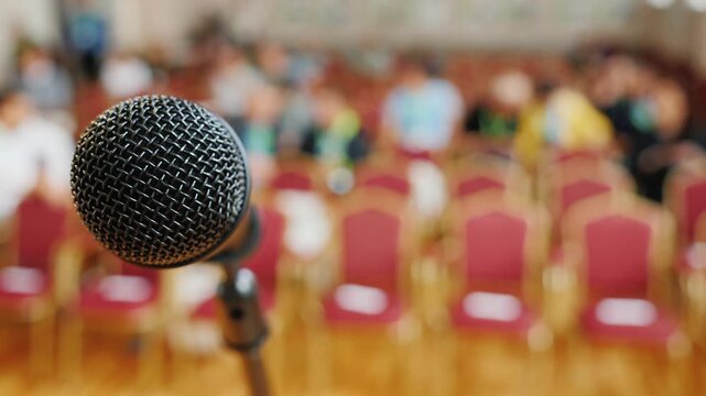 Microphone on stage with blurred audience in background ready for a live event or conference video.