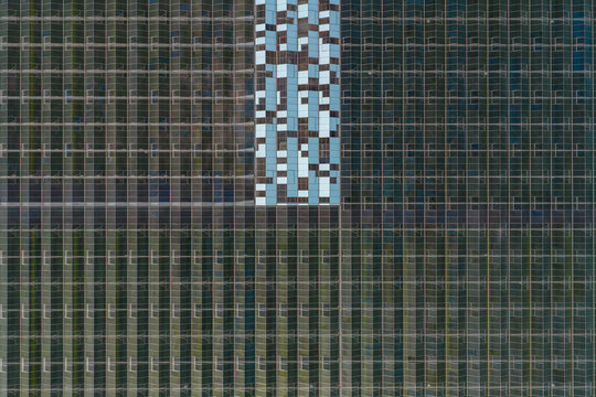 Aerial view of the geometric glass roofs of a large industrial greenhouse complex with reflective panels Hrusky, South Moravian Region, Czechia.