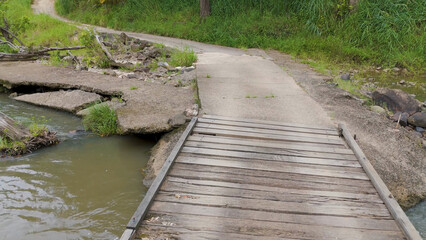 Naklejka premium Small Wooden Bridge and Concrete Path Over Tweed River in Uki