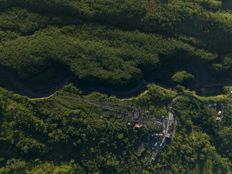 Aerial view of Bunker Kaliadem Merapi surrounded by dense tropical forest, winding roads and cold lava rivers on the slopes of Mount Merapi, Pakem, Yogyakarta, Indonesia.