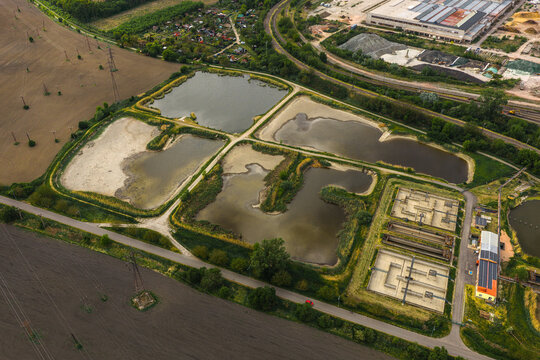 Aerial view of Tepelna elektrarna Hodonin water treatment basins and settling ponds surrounded by green fields and industrial infrastructure in Hodonin, Jihomoravsky kraj, Czechia.