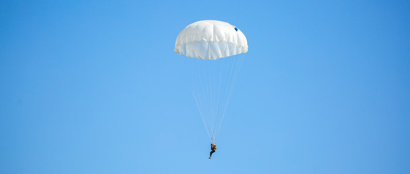 Skydiving. Flying parachutists against the background of the blue sky and mountains. Extreme sport and entertainment.