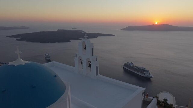 Drone Orbit Around Three Bells Chapel Belfry in Santorini at SunsetDrone orbiting the belfry of the three bells chapel in Santorini, revealing the sunset over the caldera, dramatic cliffs, and the dee