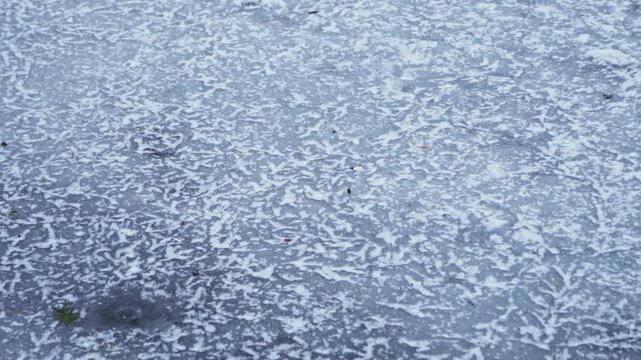 4K close up, detail video a beautiful texture of frozen water forming frost, detailed ice crystals and covered with snow on a dark, cold, gloomy, lonely winter day in nature.