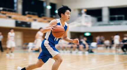 Fototapeta premium バスケットボールの試合でドリブルをする男子学生