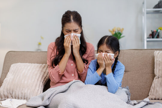 Mother and daughter experiencing cold flu symptoms at home