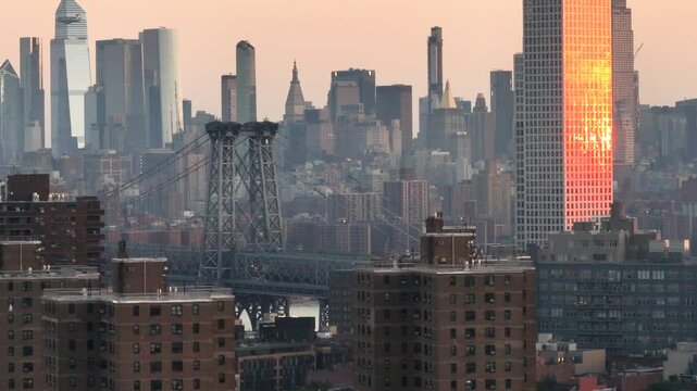 New York city skyline at sunset from the rooftop of a building showing the Manhattan bridge and skyscrapers.