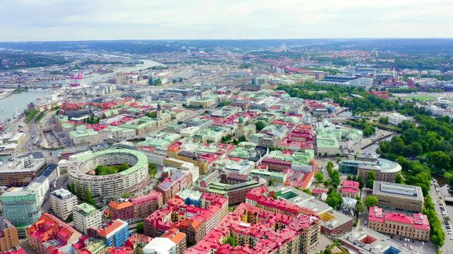 Gothenburg, Sweden. Aerial panorama of the city center with red and green rooftops, the curved Kviberg residential block, and the Gota Alv river under an overcast summer sky.. Drone footage
