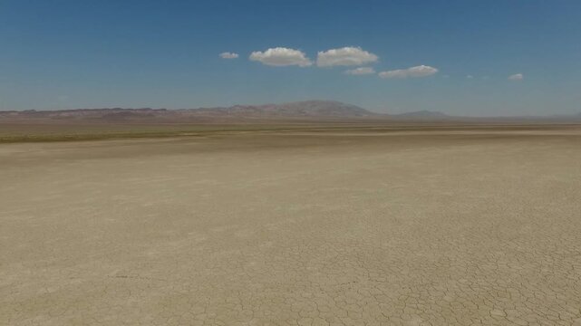 Close aerial perspective highlights sharp angular fissures cutting through the salt crust with tiny dust devils swirling in the hot arid air of central Iran stock video.