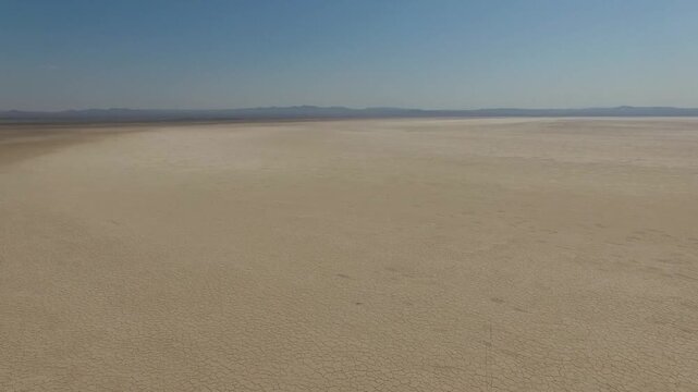 Aerial perspective highlights uniform polygon cracks across endless salt flat with no signs of life and intense glare from the sun in central Iranian desert stock footage.