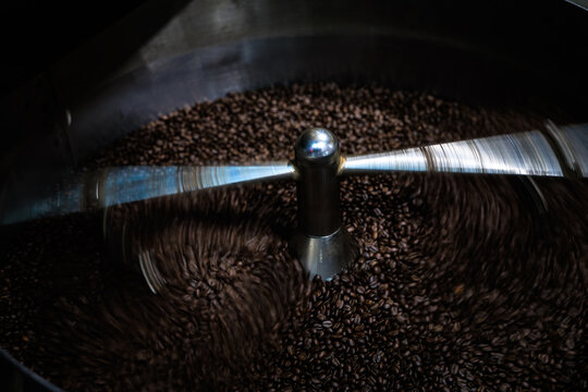 Industrial Metal Arm Agitator Stirs Dark Roasted Coffee Beans Inside A Cooling Tray