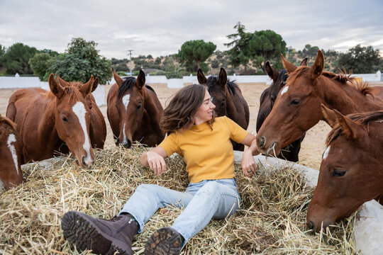 Woman relaxing in hay with horse in outdoor stable