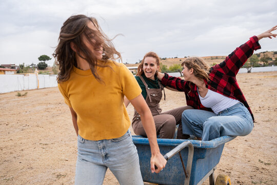Three young woman having fun riding in a wheelbarrow