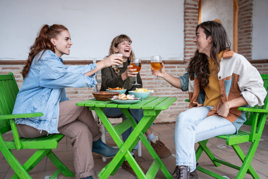 Friends toasting beer at outdoor cafe table with snacks