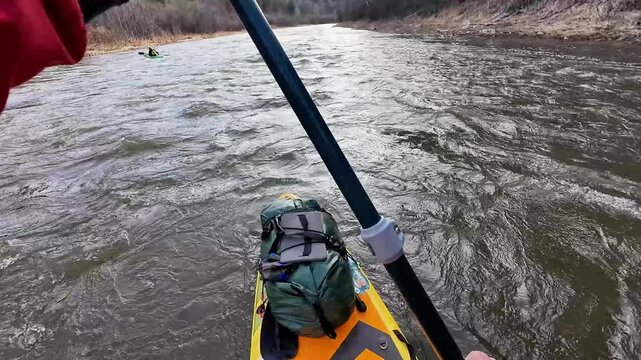 Rapid river paddling. Kayak navigating turbulent rapids. Vigorous paddler maneuvering through stormy currents. Skilled kayaker controlling boat on rough and swirling waters