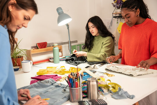 Multiethnic women sewing garment in creative atelier