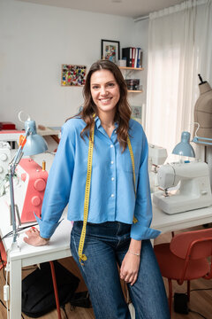Smiling fashion designer in atelier with sewing machine