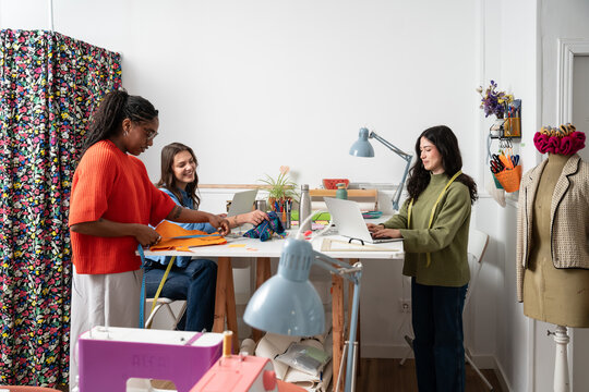 Multiethnic women planning and designing fashion in atelier