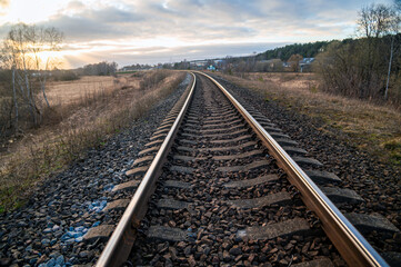 Obraz premium Railway tracks stretch through a quiet landscape during early evening light in the countryside