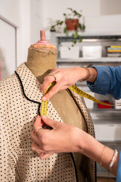 Woman measuring jacket on dress form in fashion atelier