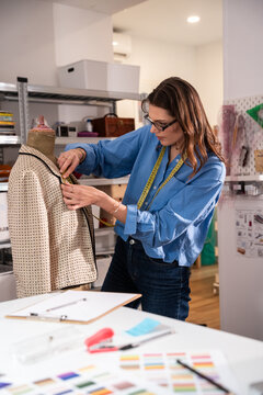 Woman fitting jacket on mannequin in fashion atelier studio
