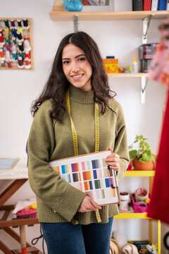 Portrait of woman designer holding color palette in fashion atelier