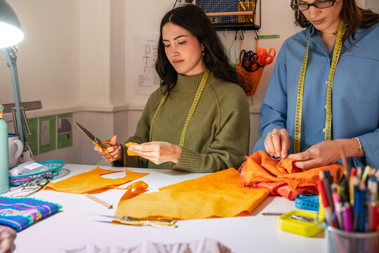 Multiethnic women sewing garment in fashion atelier