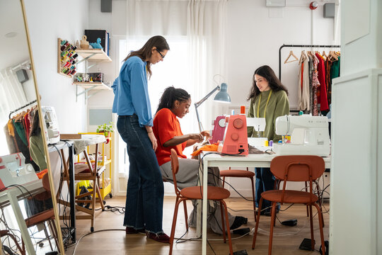 Multiethnic women sewing garments in a bright atelier